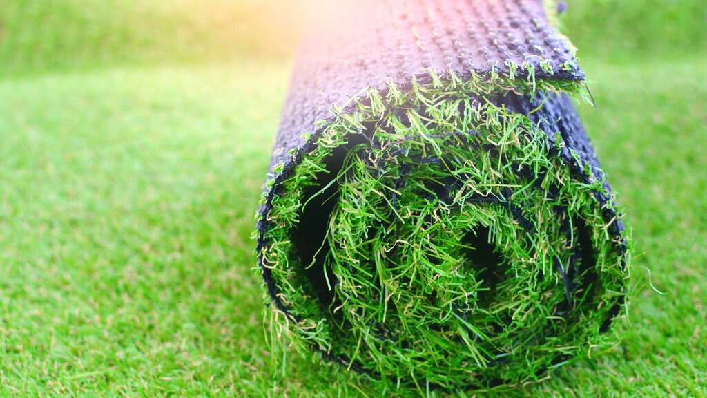 image showing a roll of artificial grass being installed